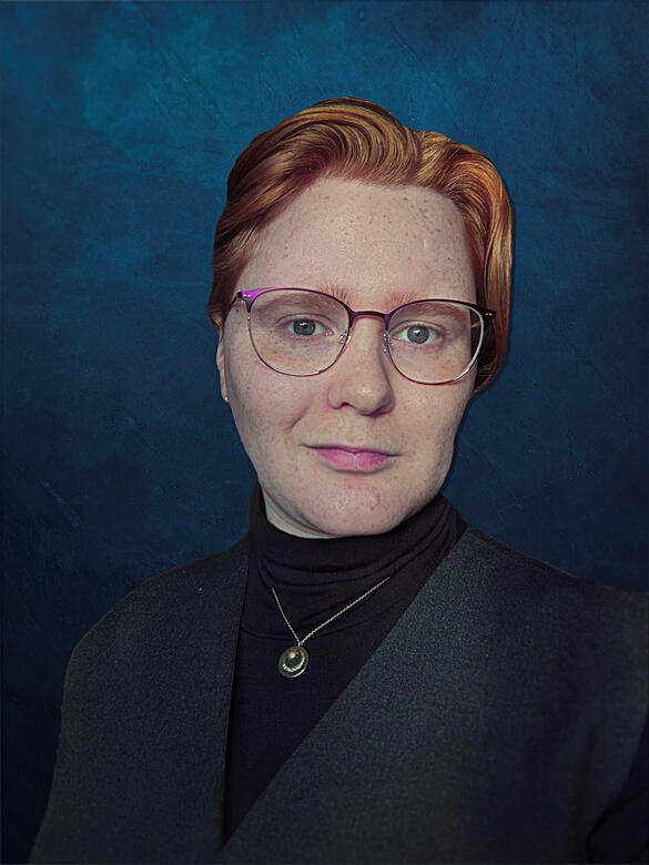 Moira Daykin A headshot of a person with short red-brown hair and light skin. She is wearing purple glasses and a black turtle-neck with a vest and necklace on top. Xie stands in front of a blue backdrop.